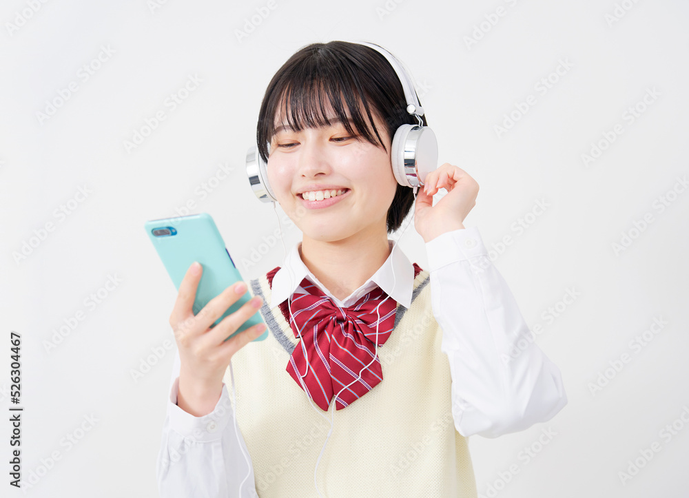 白背景でスマホを持ってヘッドホンで音楽を聴く女子高生