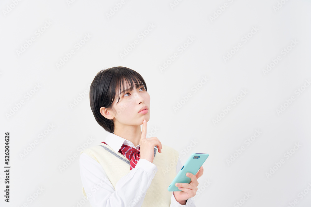 白背景でスマホを持って考える女子高生