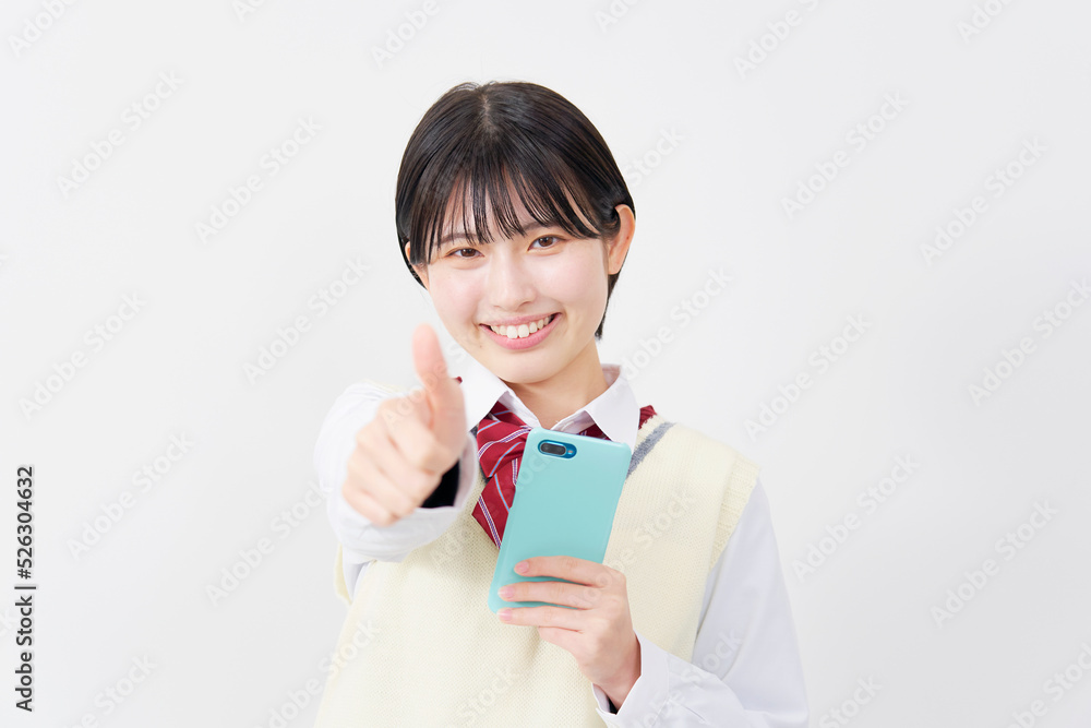 白背景でスマホを持ってグッドサインする女子高生