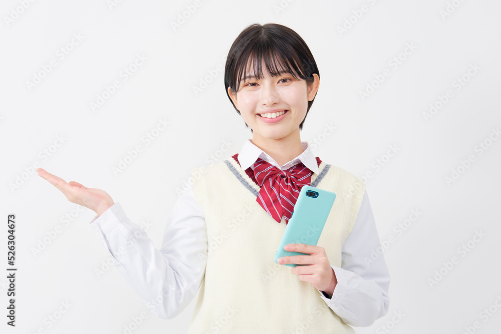 白背景でスマホを持って左を手のひらで指す女子高生