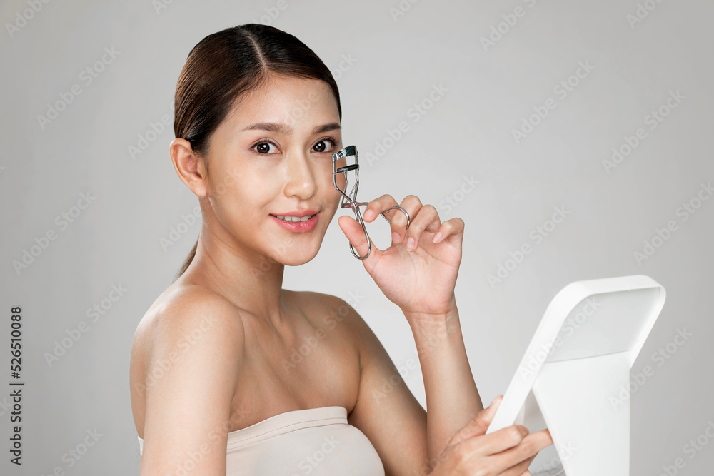 Young ardent woman model with healthy flawless fair skin and soft makeup looking at camera while usi