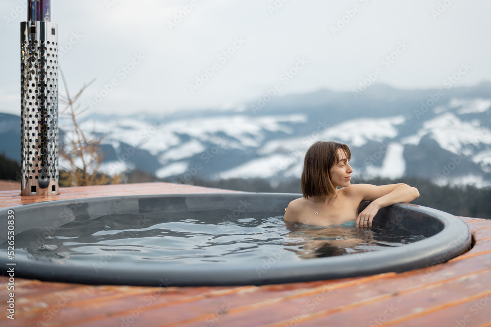 年轻女子冬天在山上的热水浴缸里洗澡。在热水浴缸里休息和恢复的概念