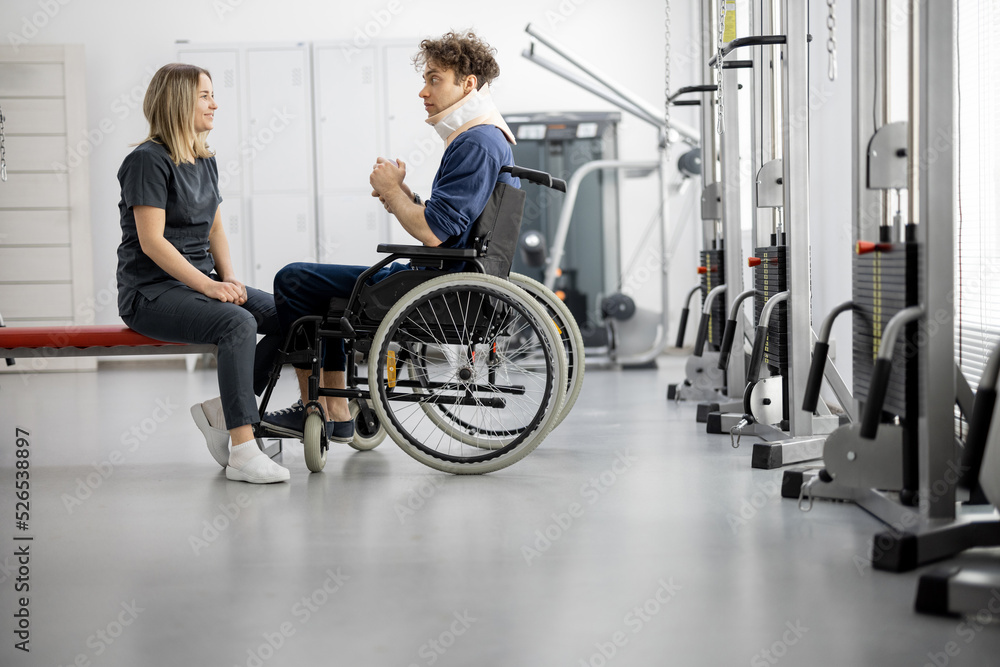 Rehabilitation specialist talking with a guy on wheelchair at rehabilitation center. Concept of ment