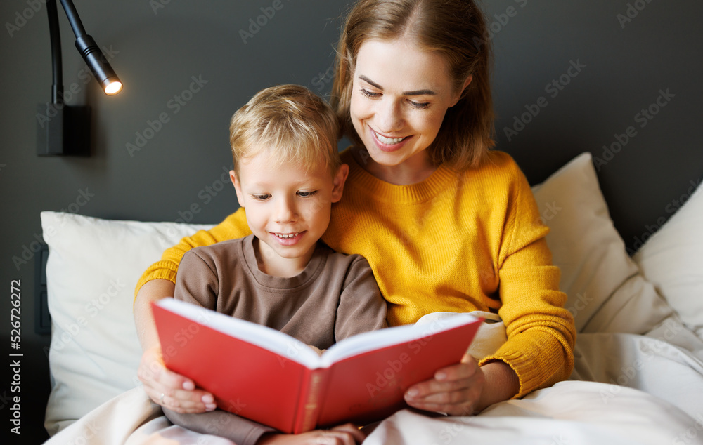 Happy mother and son reading book together on bed