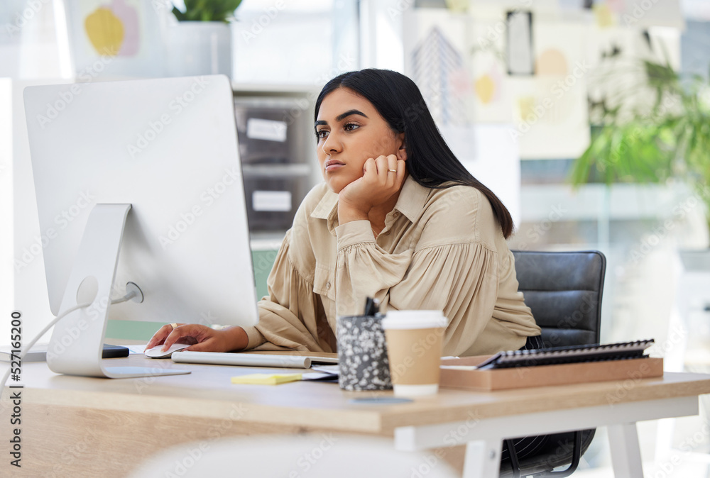 A bored, lazy and tired employee working on a computer in the office leaning on her desk. An overwor