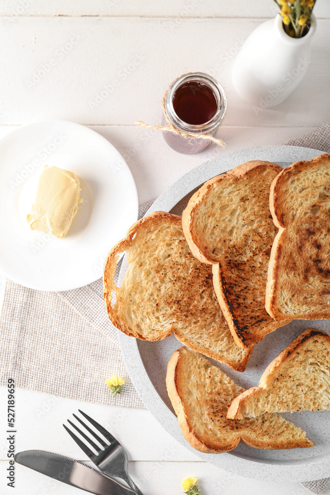 Plates with toasts, butter and maple syrup on light wooden background, closeup