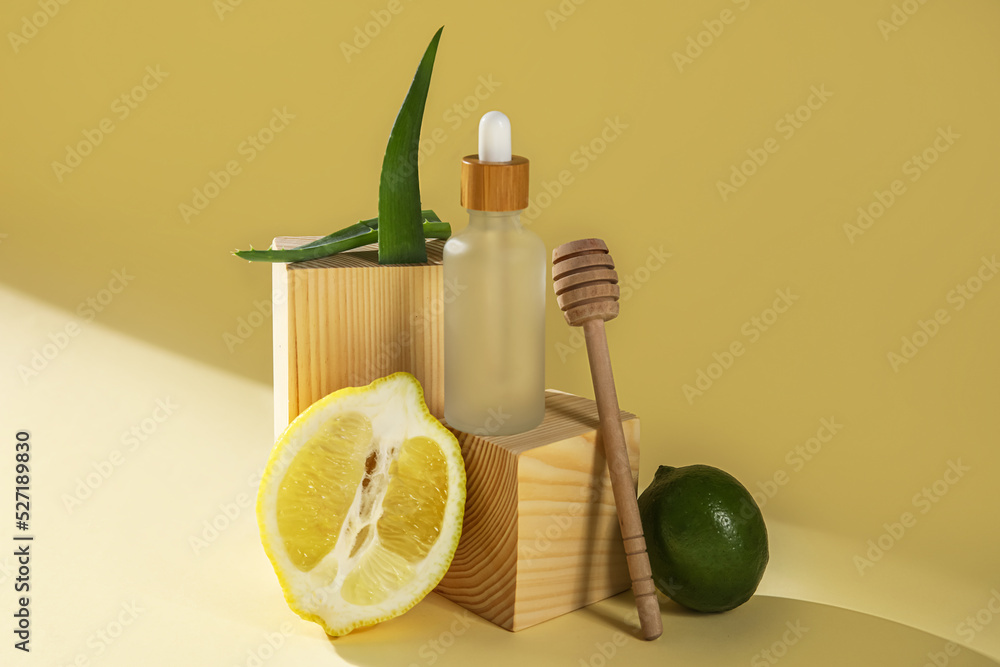 Composition with bottle of essential oil, lemon, lime and aloe leaves on color background