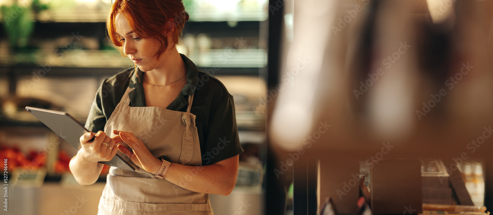 女店主在杂货店使用数字平板电脑