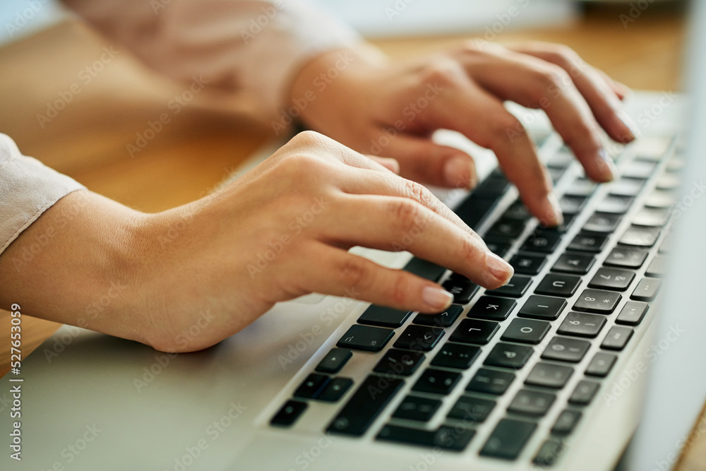 Woman typing on a laptop keyboard working on a report, email or online research for website about us