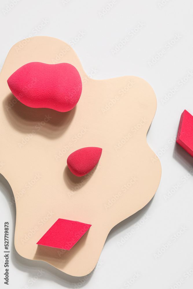 Stand with makeup sponges on light background