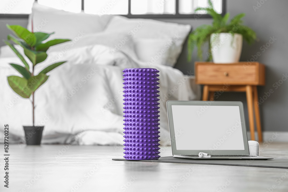 Foam roller and laptop on mat in bedroom