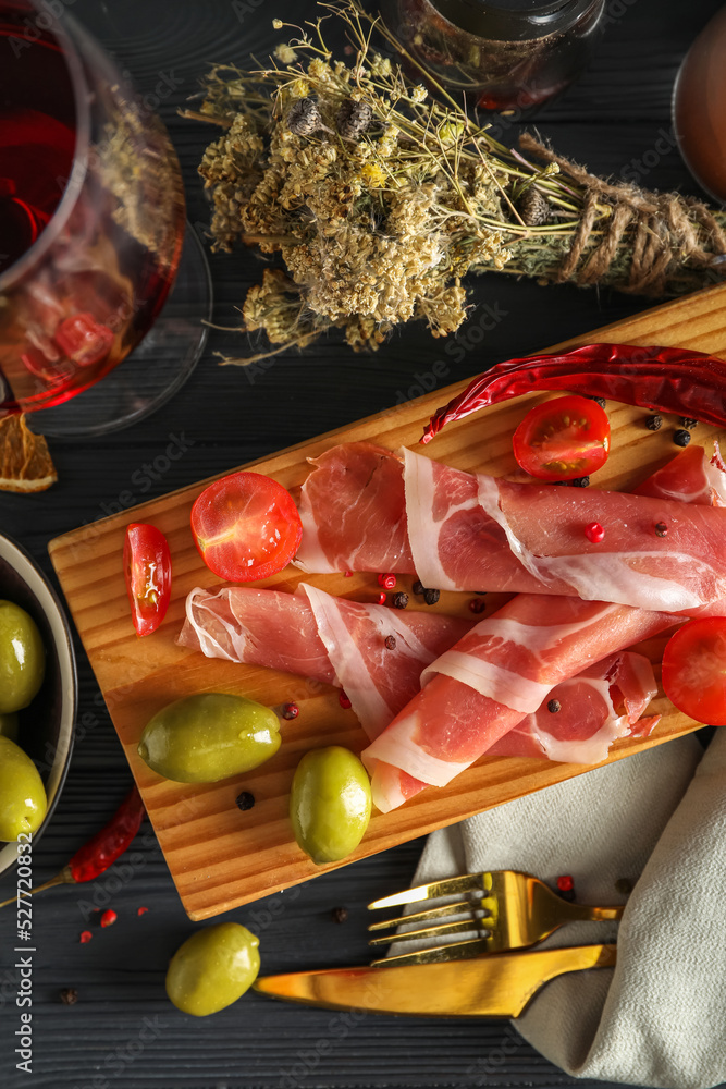 Board with delicious jamon on dark wooden table, closeup