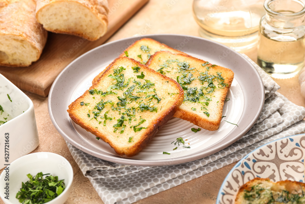 Plate with slices of delicious toasted garlic bread on table, closeup