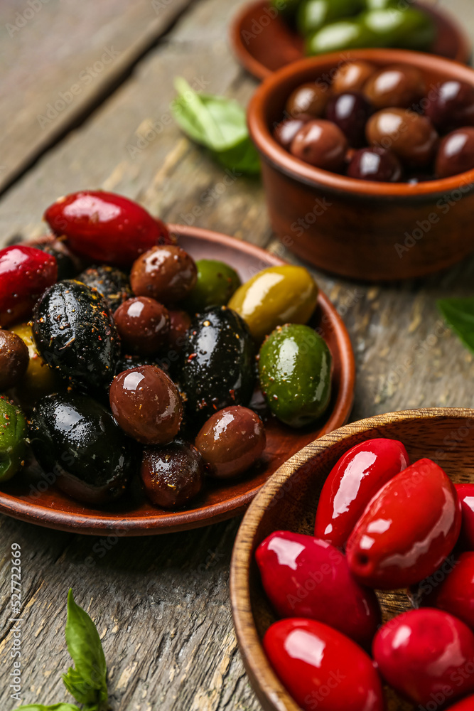 Bowls with different kinds of delicious olives on wooden background, closeup