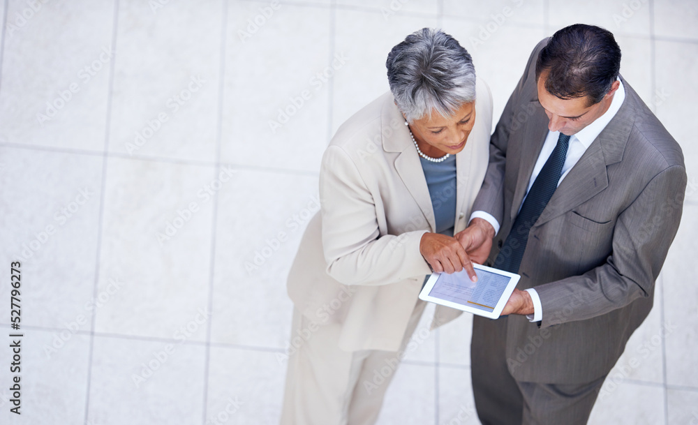 Bouncing ideas off each other. High angle shot of two business colleagues standing with a digital ta