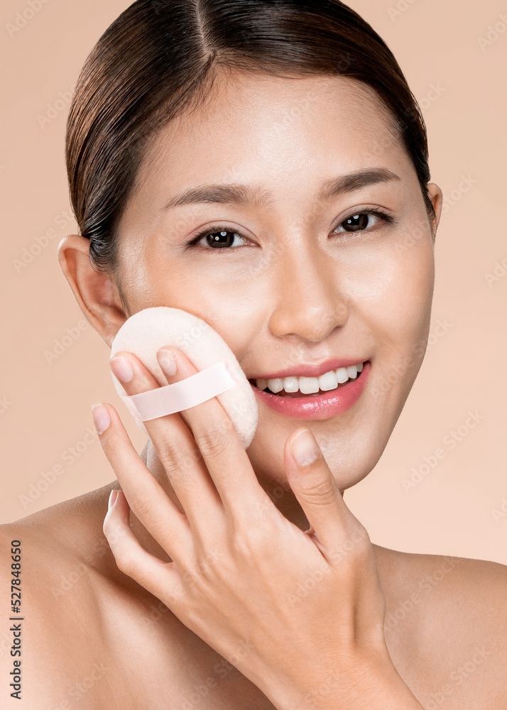 Closeup ardent woman applying her cheek with dry powder and looking at camera. Portrait of younger w