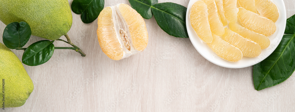 Fresh pomelo fruit on bright wooden table background.