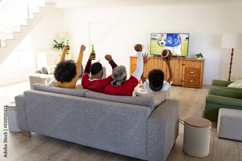 African american family sitting on the couch and watching football match on laptop