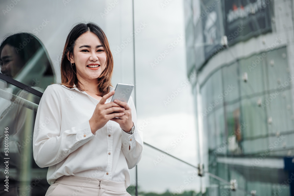 亚洲女性在航站楼门口用智能手机等候。年轻休闲商务人士的航空旅行理念