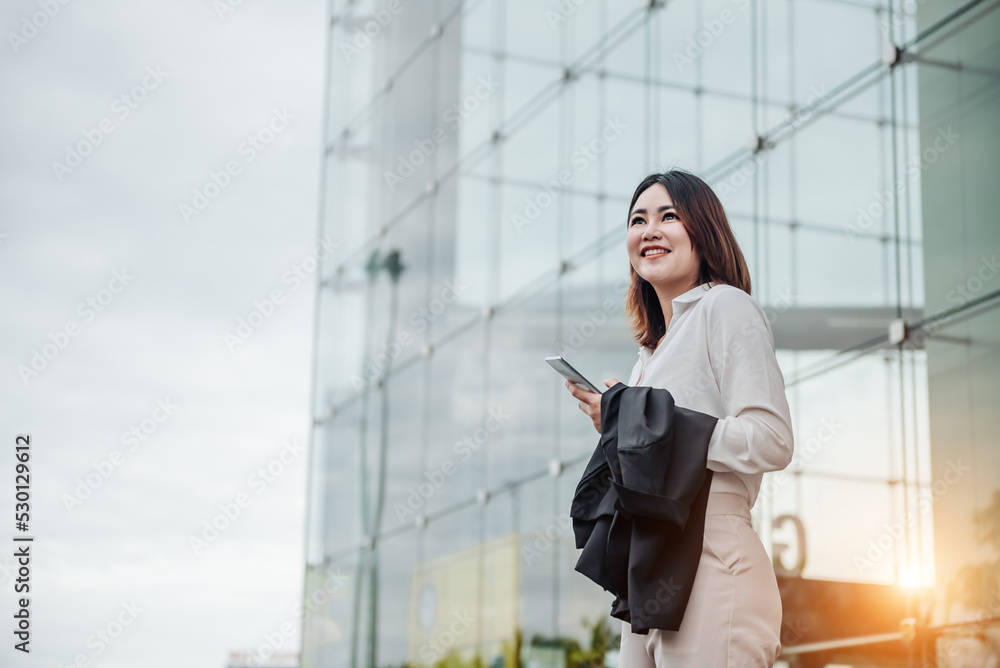 亚洲女性在航站楼门口用智能手机等候。年轻休闲商务人士的航空旅行理念