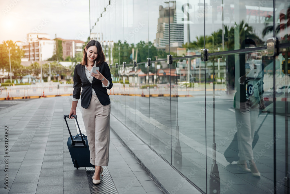 Asian woman on smart phone walking at terminal. Air travel concept with young casual business woman 