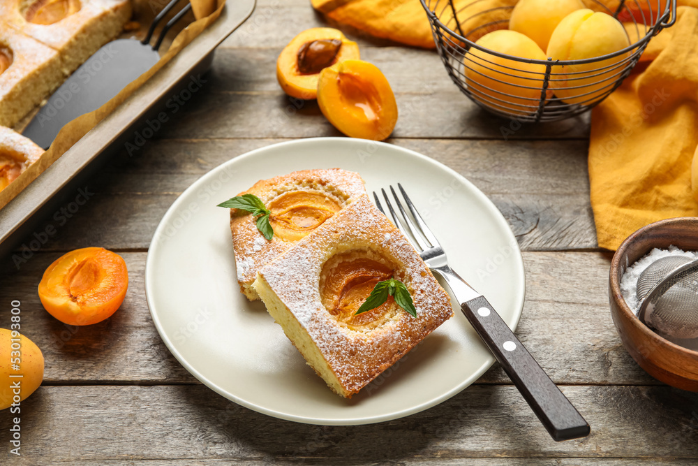 Plate with pieces of tasty apricot pie on wooden table