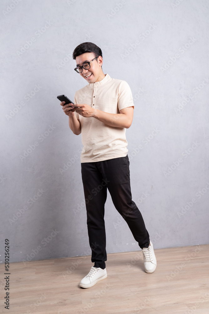 Full length image of young Asian man using smarphone