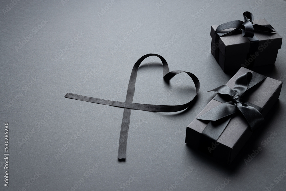 Composition of presents with ribbons and ribbon heart on gray background