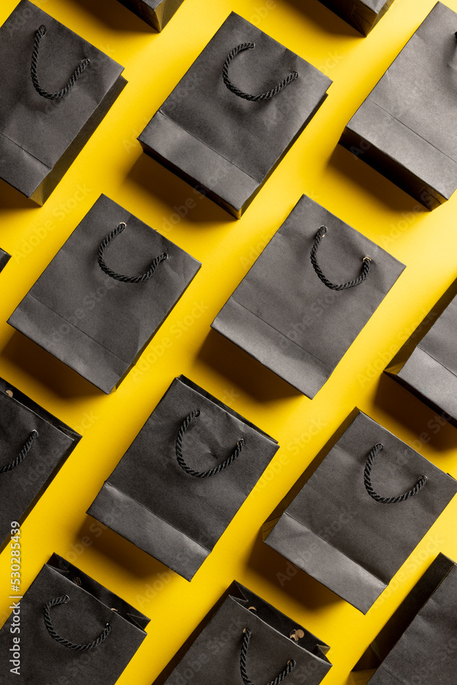 Composition of gray paper shopping bags on yellow background