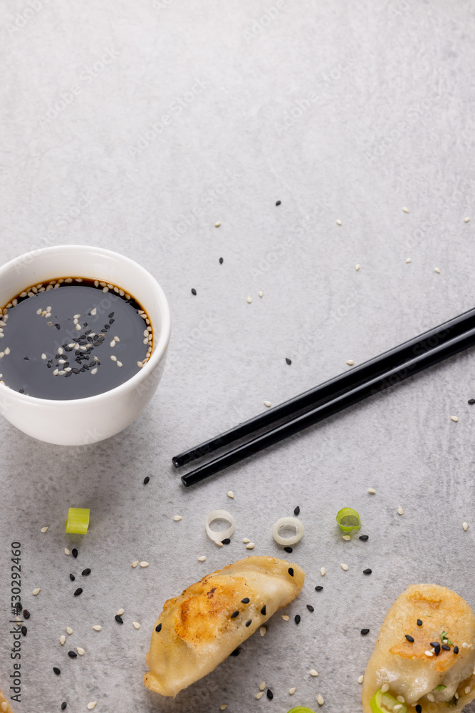 Overhead view of asian dumplings, soy sauce and chopsticks on grey background