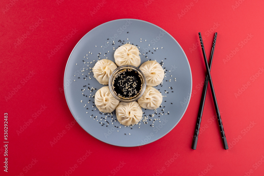 Overhead view of asian dumplings, soy sauce and chopsticks on red background