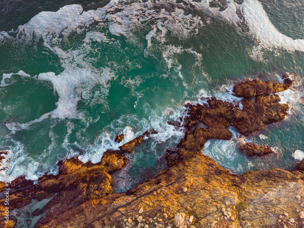 High angle view of sea waves and sea shore with rocky cliff shore