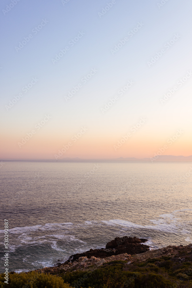 Landscape of sea waves and sea shore with rocks, blue cloudless sky and horizon