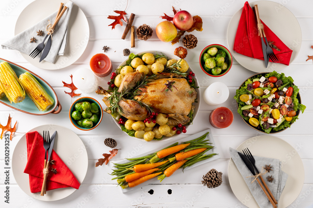 Overhead view of thanksgiving table with roast turkey, vegetables and autumn decoration on wood