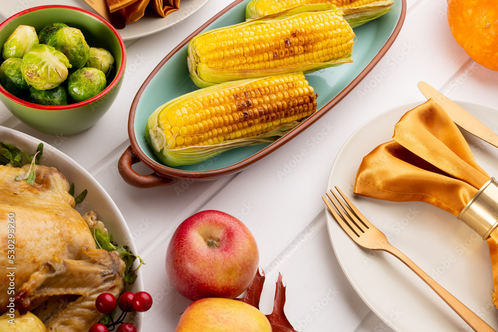 Overhead view of thanksgiving table with roast turkey, vegetables and autumn decoration on wood