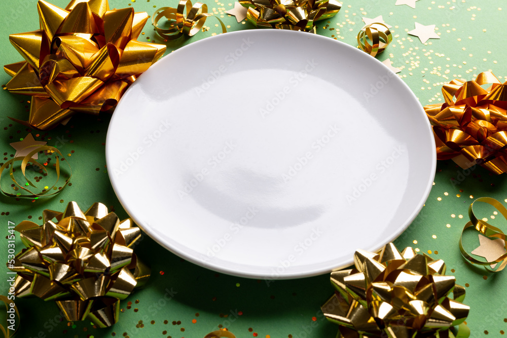 Image of christmas decoration with white plate and copy space on green background