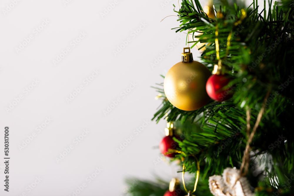 Image of christmas tree with baubles decoration and copy space on grey background