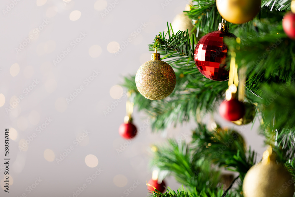 Image of christmas tree with baubles decoration and copy space on grey background