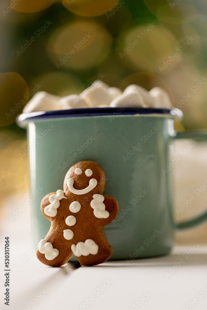 Image of green mug with christmas hot chocolate with marshmallows and gingerbread man