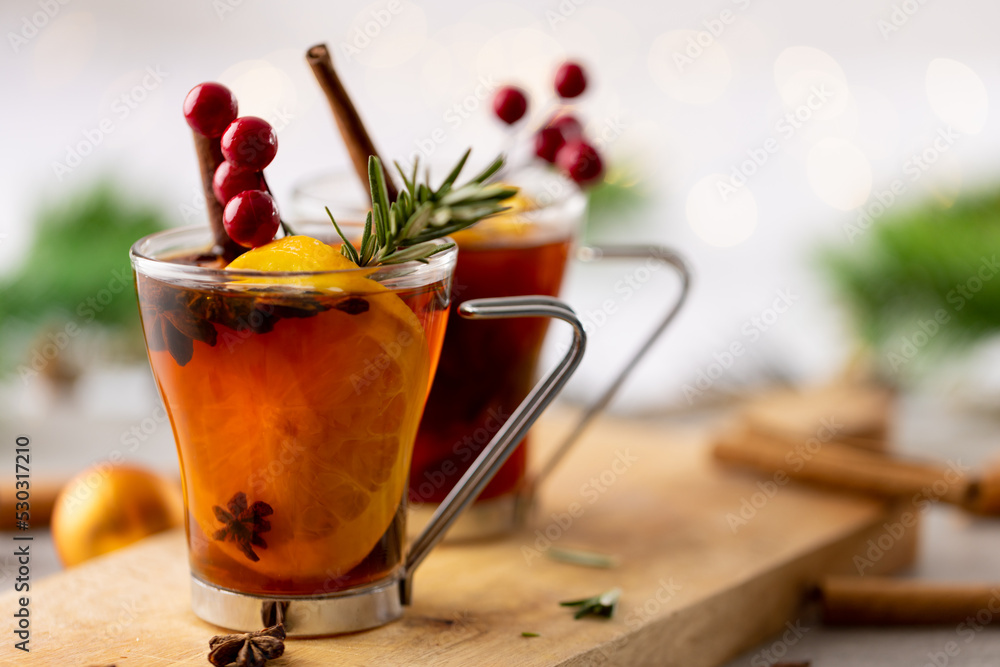 Image of two cups of tea with spices and lemon and christmas decorations with copy space