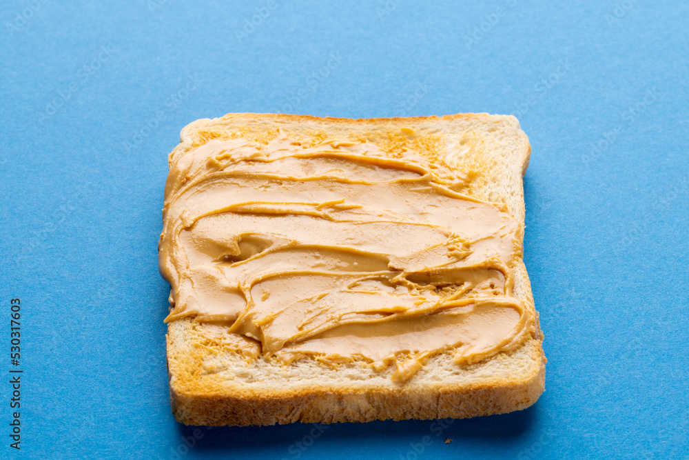 Image of bread slice with peanut butter on blue background