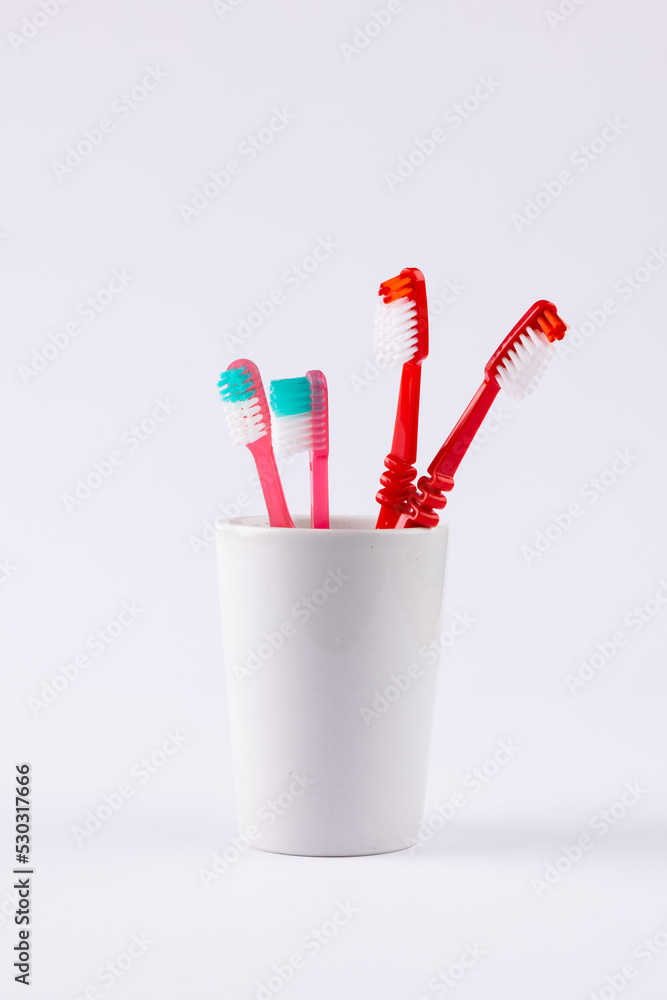 Vertical image of toothbrushes in cup on grey background