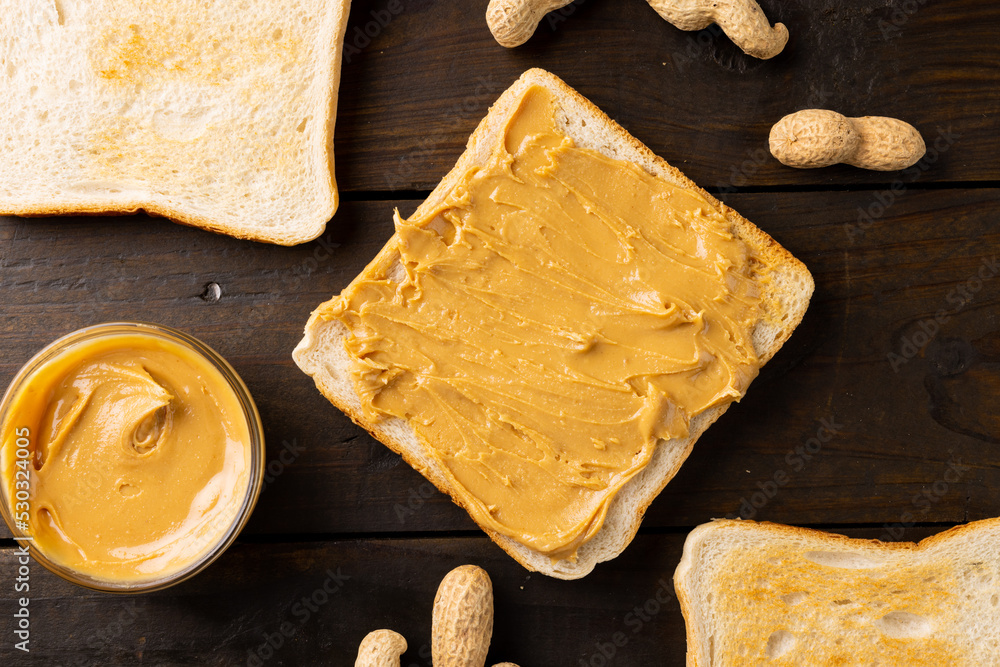 Image of bowl and bread slice with peanut butter on wooden surface