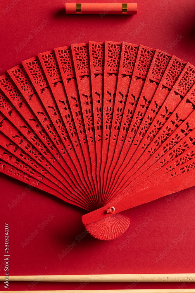 Composition of traditional chinese fan and decorations on red background