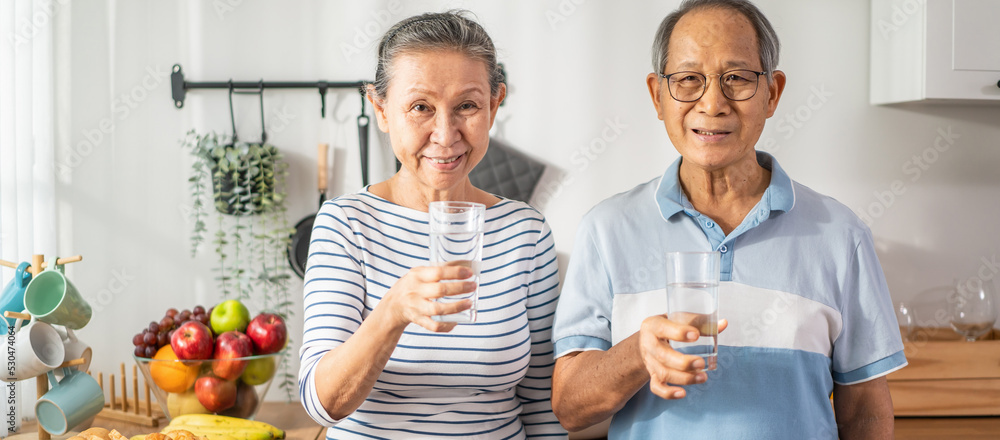 亚洲老年夫妇在厨房里喝一杯水的肖像。