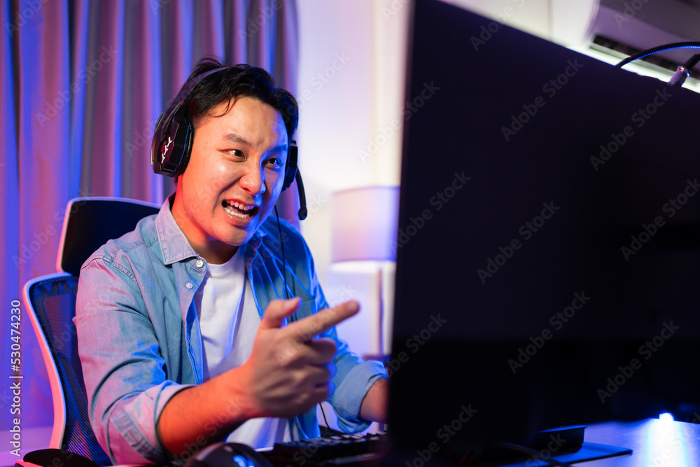 Asian attractive Esport male gamer play online video game on computer.