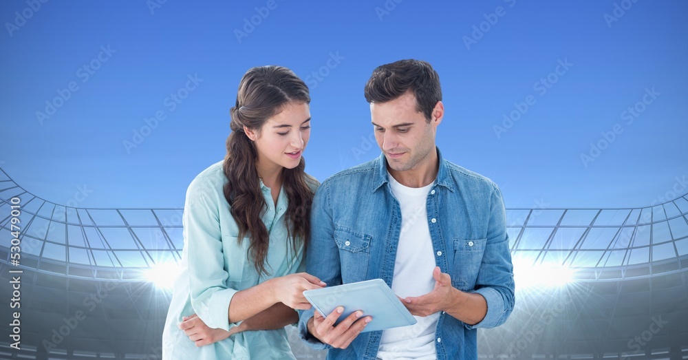 Composite image of caucasian couple using digital tablet against sports stadium with copy space