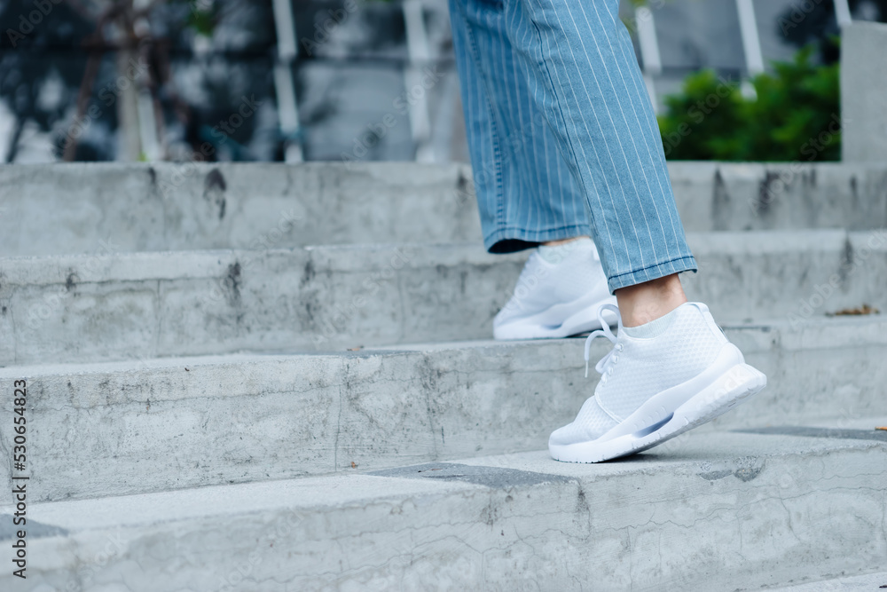 Close up white shoes of woman walking on staire in the outdoor park in sunny day