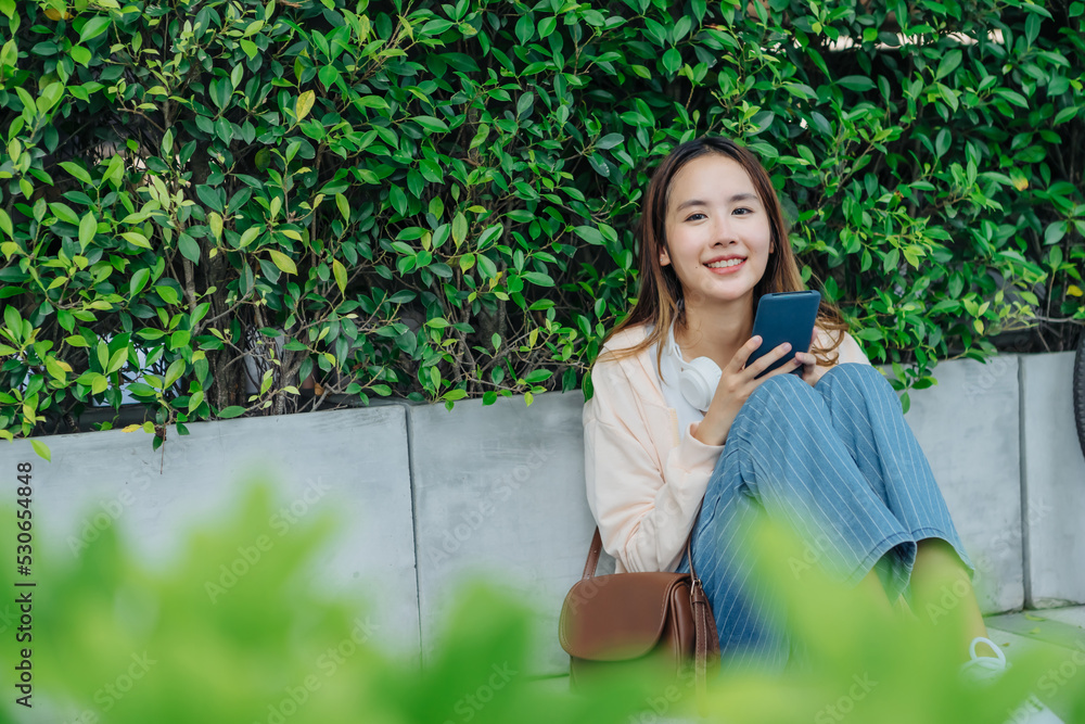 美丽的亚洲女人用手机耳机听最喜欢的音乐，幸福放松