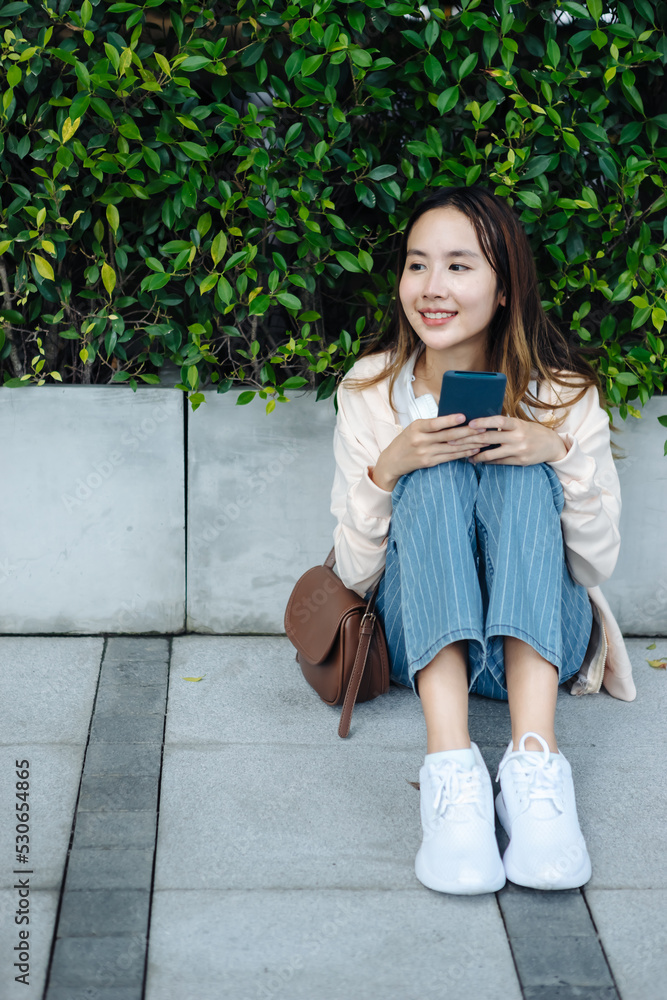 美丽的亚洲女人用手机耳机听最喜欢的音乐，幸福放松